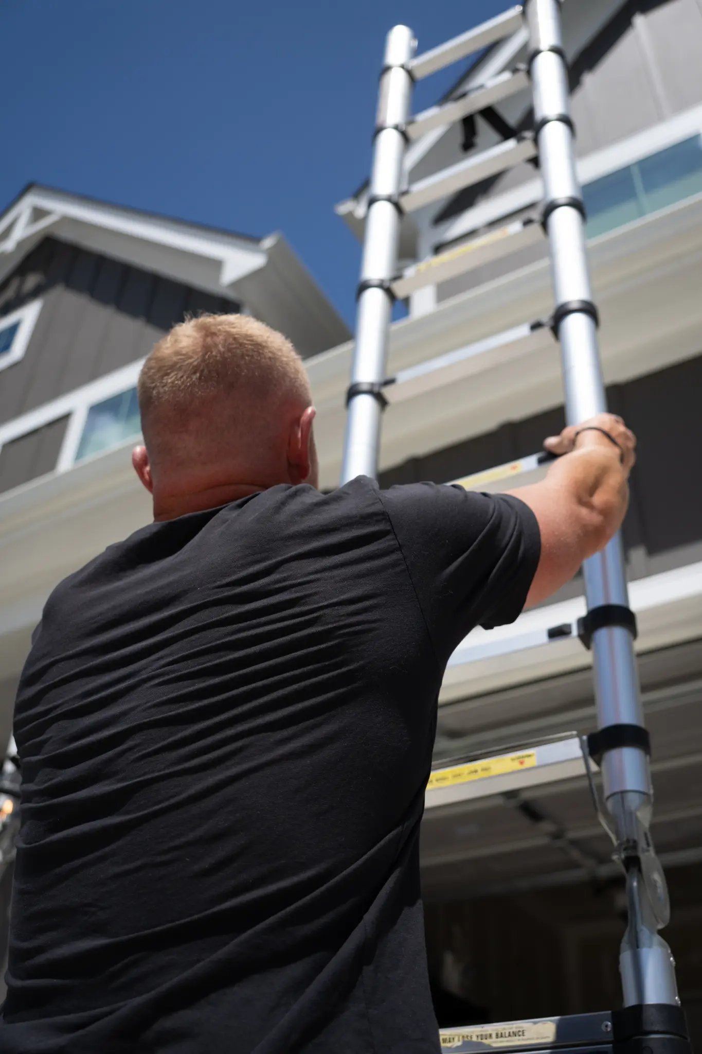 Inspector working at a home's roofline with a ladder